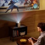 A compact silver LG CineBeam S Mini UST 4K projector projecting a vibrant 100-inch image from a short distance.